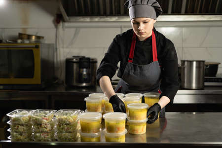 Food delivery to the restaurant. female chef prepares food in a restaurant and prepares it in disposable dishes.の写真素材