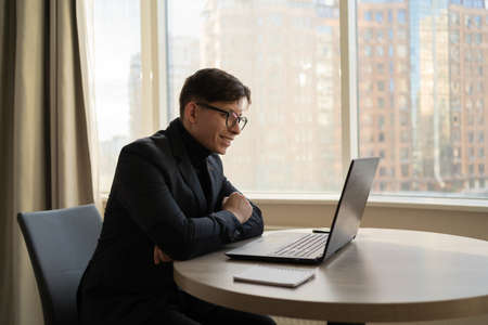 Serious businessman using laptop in bright office space. Video call entrepreneur conference online. concept of using technologyの写真素材