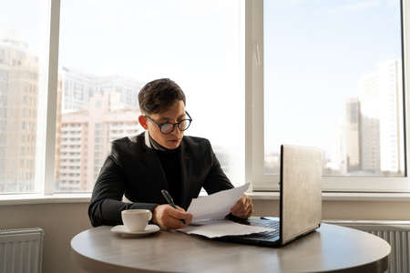 Frustrated man calculating bills and tax expenses, businessman wearing glasses bankruptcy office, financial crisis, problems at work, technology online work.の写真素材