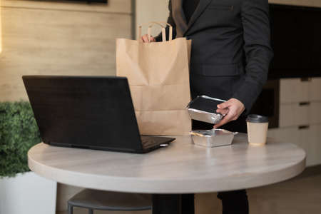 home office unpacking takeaway food or lunch delivery, male hands pulling containers and dishes with vegetarian food out of the package, food delivery home conceptの写真素材