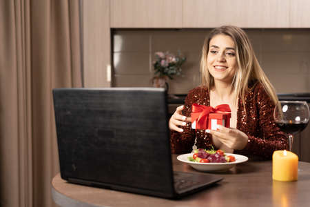 Valentines day at home online, beautiful girl with gift video call on laptop, virtual date february 14, lovers videochat, valentines day celebration conceptの写真素材