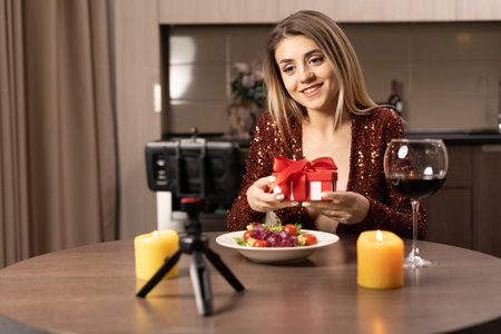 date online. women at home at the table and making a video zoom call using the application on the smartphone. Opens a gift online. concept of remote celebration of anniversary or valentines dayの写真素材