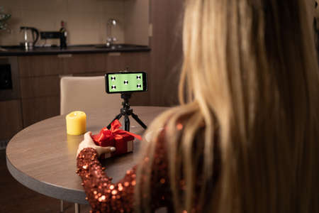 View your smartphone screen over your shoulder. Young woman makes a video call on a green screen of a smartphone with tracking markers. Chrome plated key background of the computer screen.の写真素材