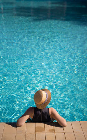 Young asian woman in hat relaxing in swimming pool spa resort, top view. vacation and relaxation conceptの写真素材