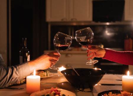 Couple clinking glasses of red wine celebrating valentines day, romantic date and dinner for two, alcohol in glass, anniversary or valentines dayの写真素材