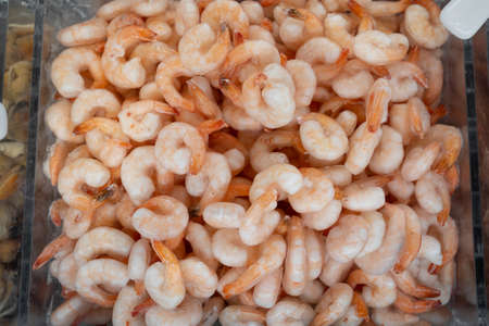 of a heap of frozen orange shrimp. Peeled shrimp, leaving only the tails. Natural seafood background. Showcase refrigerator.の写真素材