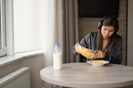 Smiling young caucasian man pouring corn flakes into a plate. The girl has breakfast in the morning...