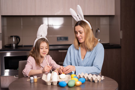Mother and daughter paint Easter eggs. Happy family is preparing for Easter. Cute little girl with bunny ears on Easter day. Preparation for Easter. copyspace.の写真素材