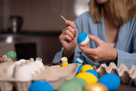 Hands paint Easter eggs in a modern style with green paint. creativity with children, traditional symbols. Preparation for Easter.の写真素材