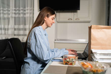Home food delivery concept. Woman at the table with disposable containers of healthy food for weight loss. online shopping. Restaurant order delivery. Vegetable lunch in disposable tablewareの写真素材