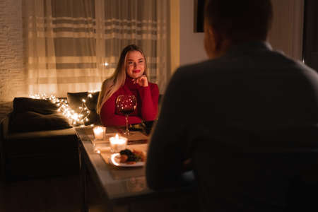 Romantic dinner for two, lovers celebrate valentines day, couple having dinner at home by candlelight, man and woman having a date with wineの写真素材