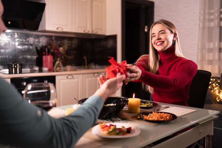 Valentines day dinner for two, a woman gives her husband a present at the table, a gift for a man on his birthday or anniversaryの写真素材