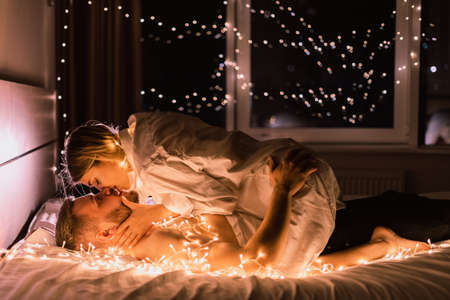 couple in love man and woman lie in bed at night and kiss. valentine's day or anniversary celebration concept. copyspace.の写真素材