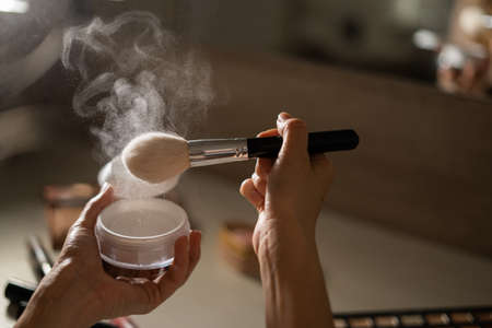 powder sprayed with a professional cosmetic brush, decorative cosmetics in the form of powder with a brush for applying it. Womens handsの写真素材