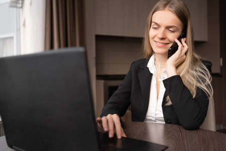 business concept. Close-up, young smiling businesswoman in home office talking on cell phone, remote work and freelancer woman working at homeの写真素材