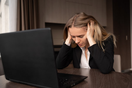 Sick woman working at laptop having headache tired at home office, migraine and menstruation, health medical consultation, electromagnetic radiationの写真素材