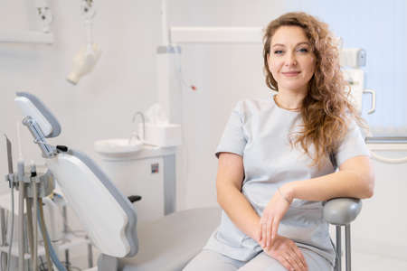 Portrait of a female dentist. She is sitting on a chair in her dentist's office. copy spaceの写真素材