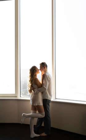 A young couple in love in the morning in casual clothes stands near the window. copyspace.の写真素材