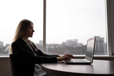 Business woman using laptop computer while sitting in the office near the window. People, business and technology concept.の写真素材