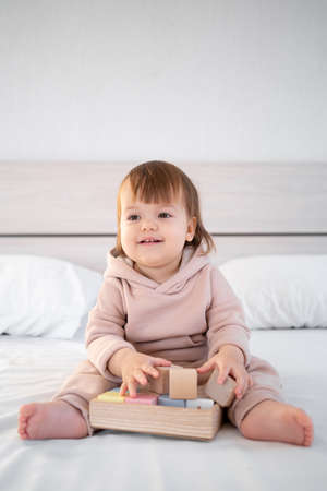 little cute kid playing with toy cubes sitting on bed at home.の写真素材