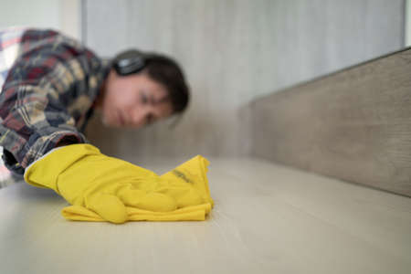 Close up hands in rubber protective yellow gloves cleaning the white surface with a rag. House, housekeeping concept. copyspace.の写真素材