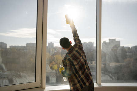 man washing windows at home, casual wear shirt, yellow rubber gloves, house cleaning concept. copyspace.の写真素材