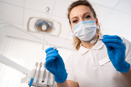 Dentist woman alone holding dental instruments, looking at the camera. Personal or patient point of...