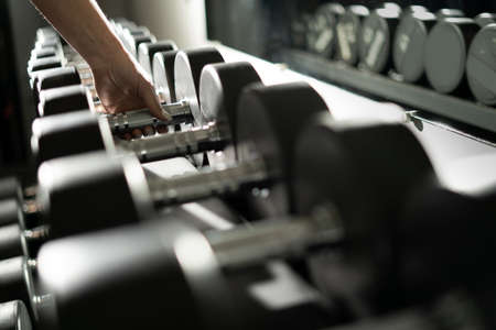 female hand takes a dumbbell in the gym. sport and healthy lifestyle concept.の写真素材