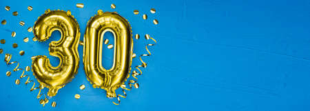 golden foil balloon number thirty. Birthday or anniversary card with the inscription 30. blue concrete background. Anniversary celebration. Banner. copy spaceの写真素材