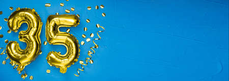 golden foil balloon number thirty five. Birthday or anniversary card with the inscription 35. blue concrete background. Anniversary celebration. Banner. copy spaceの写真素材