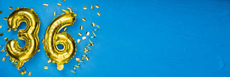 golden foil balloon number thirty six. Birthday or anniversary card with the inscription 36. blue concrete background. Anniversary celebration. Banner. copy spaceの写真素材