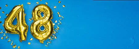 golden foil balloon number forty eight. Birthday or anniversary card with the inscription 48. blue concrete background. Anniversary celebration. Banner. copy spaceの写真素材