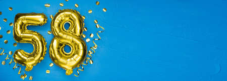 golden foil balloon number fifty eight. Birthday or anniversary card with the inscription 58. blue concrete background. Anniversary celebration. Banner. copy spaceの写真素材