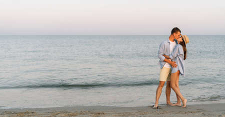 Couple in love man and woman experiencing romantic tender moments at sunset on the beach - Young lovers in love passionately kissing - love concept - soft focus on them. Banner. copyspace.の写真素材