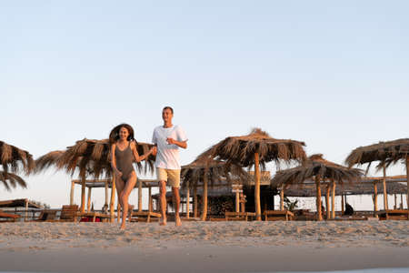 A happy couple man and woman run along the tropical beach towards the water. copyspace.の写真素材