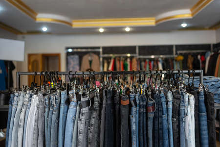 shop of fashionable European clothes, branded jeans in the boutique on hangers, blue jeans. Clothes backgroundの写真素材
