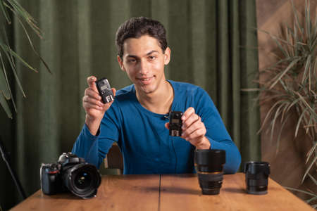 arab Guy-photographer is recording a video lesson for photographers holding radio synchronizers for flashes in his hands. Online photography training, courses for photographers. webcam viewの写真素材