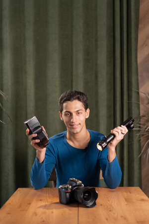 arab Guy-photographer is recording a video tutorial for photographers holding a lantern and a flashlight between continuous and pulsed light. photography courses. webcam viewの写真素材