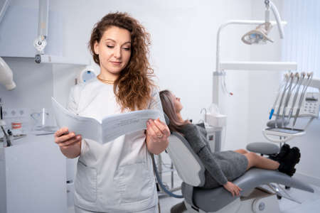 Portrait of a female dentist in a clinic. dental clinic and oral health concept. the doctor examines the client's card. copyspace.の写真素材