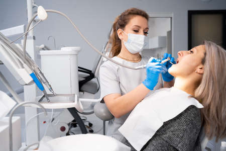 Dentist and patient in the medical center. The doctor treats the teeth of a young woman with a dental drill. Reception of an orthodontist and a prosthetist. Hygiene and healthy teeth. copyspace.の写真素材