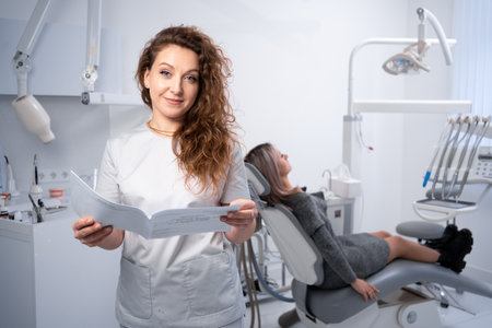 Portrait of a female dentist in a clinic. dental clinic and oral health concept. a doctor with a client's card looks at the camera. copyspace.の写真素材