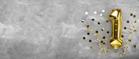 Yellow foil balloon number, number one on a concrete background. Birthday card with lettering 1. Anniversary concept. for anniversary, birthday, new year celebration. banner, copy space.の写真素材