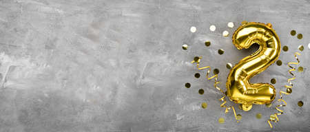 Yellow foil balloon number, number two on a concrete background. Birthday card with lettering 2. Anniversary concept. for anniversary, birthday, new year celebration. banner, copy space.の写真素材