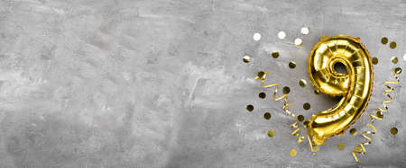 Yellow foil balloon number, number nine on a concrete background. Birthday card with inscription 9. Anniversary concept. for anniversary, birthday, new year celebration. banner, copy space.の写真素材