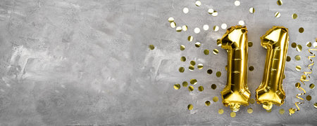Yellow foil balloon number, number eleven on a concrete background. 11th birthday card. Anniversary...