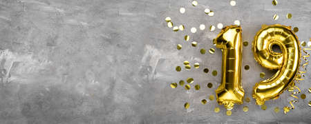 Yellow foil balloon number, number nineteen on a concrete background. Birthday card with inscription 19. Anniversary concept. for anniversary, birthday, new year celebration. banner, copy space.の写真素材