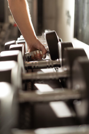 close-up of a female hand takes a dumbbell in the gym. sport and healthy lifestyle concept.の写真素材