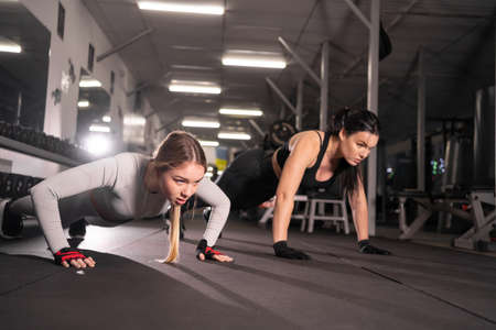 two happy young women in the gym doing push up exercise.Healthy lifestyle, gymnastics conceptの写真素材