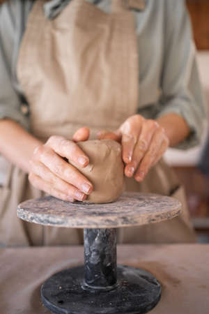 Creative handicraft process woman artist uses tool for shaping and hand sculpting pottery. working table in a workshop where a potter works with raw materials to create handicraft potteryの写真素材
