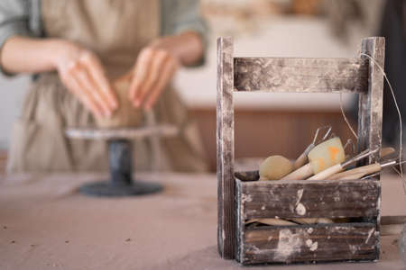 Close-up of an artisan woman's hand working with clay in a pottery workshop wearing an apron creates a handmade ceramic bowl. The concept of skill and entrepreneurship. copyspace.の写真素材